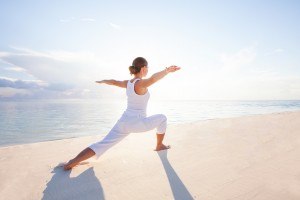 Frau macht Yoga am Strand