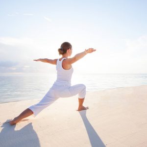 Frau macht Yoga am Strand