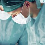 Operationsärzte in Kitteln und mit Mundschutz